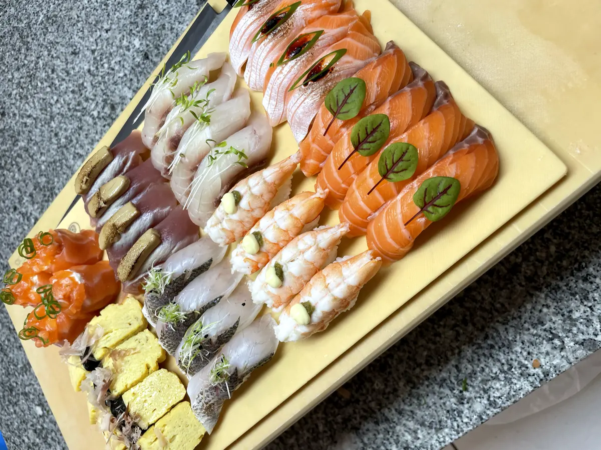 Rangées de nigiris saumon, crevette, daurade et tamago sur planche de travail