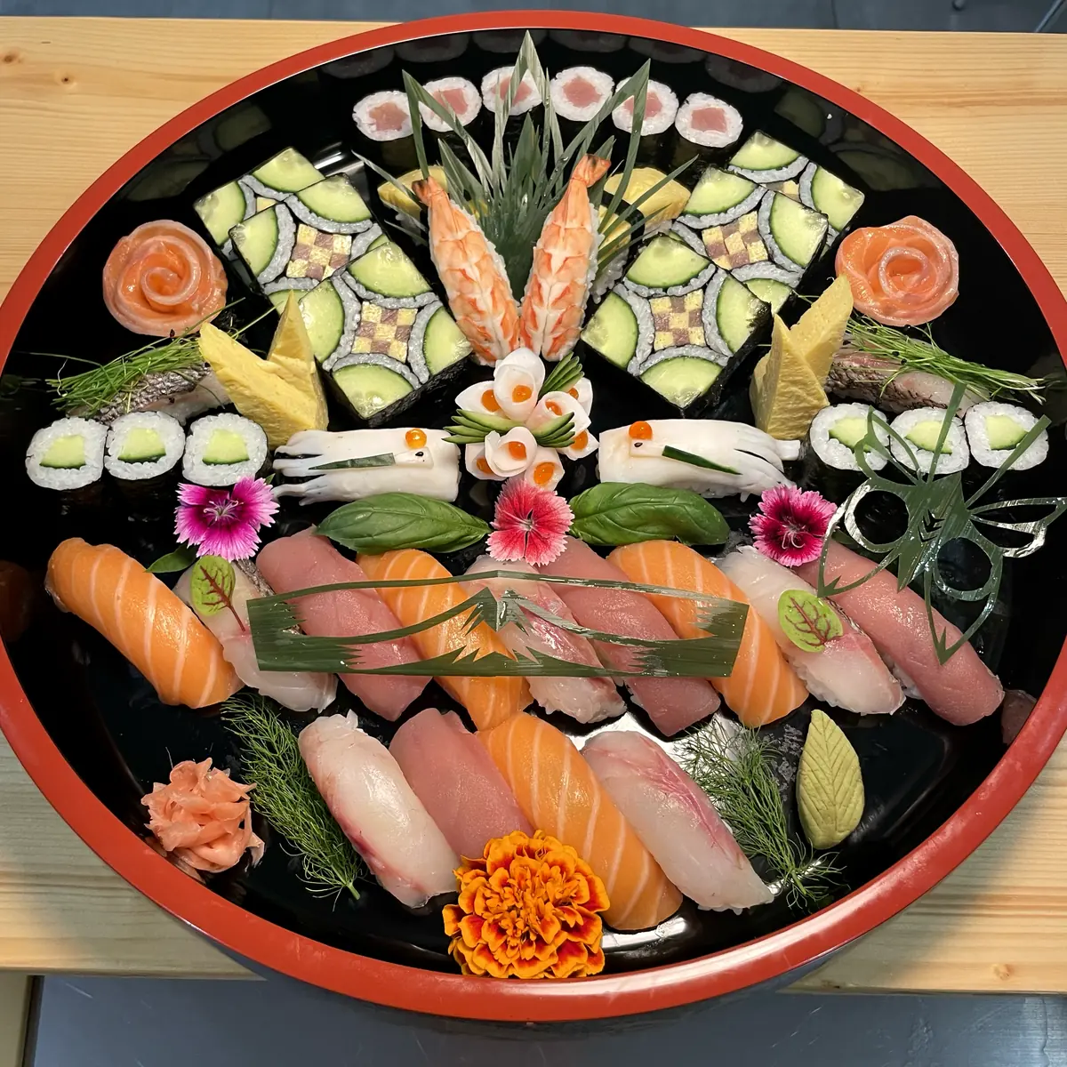 Plateau rond laqué garni de nigiris, makis et gunkans, décoré de fleurs comestibles