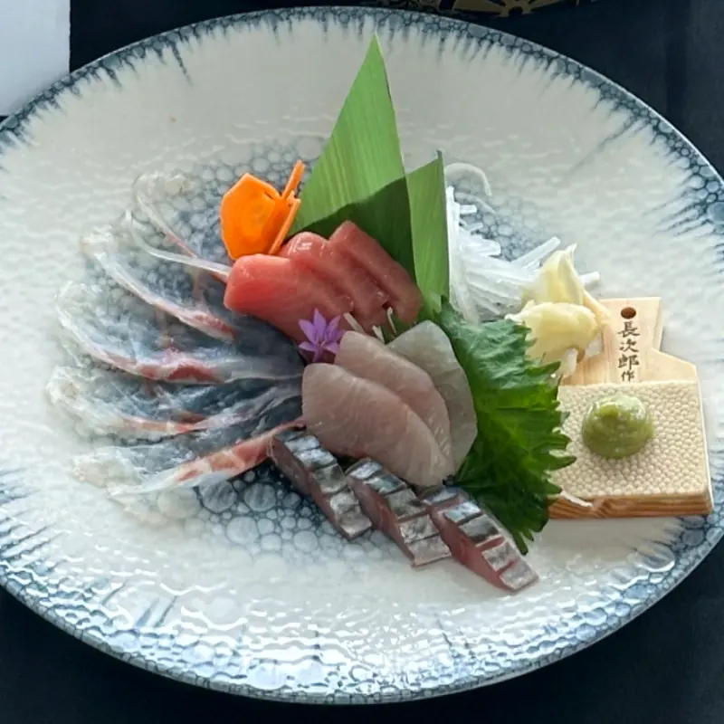 Assiette de sashimi : thon rouge, sériole, maquereau et daurade tranchés sur céramique japonaise